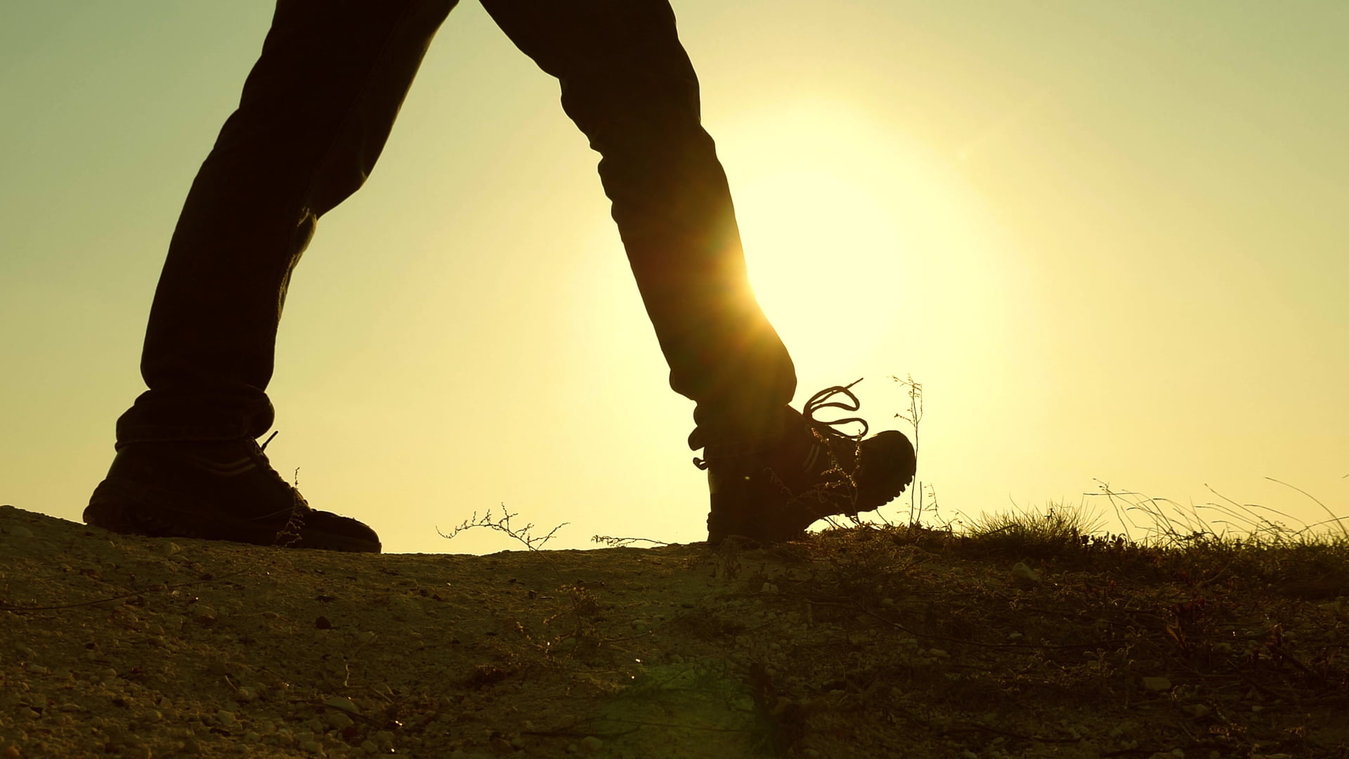 a courageous man-traveler, climbing to top of a mountain, walking along a path along a dangerous rocky ridge. Steep wall that opens a beautiful sunset view. slow motion. close-up. marche a pied